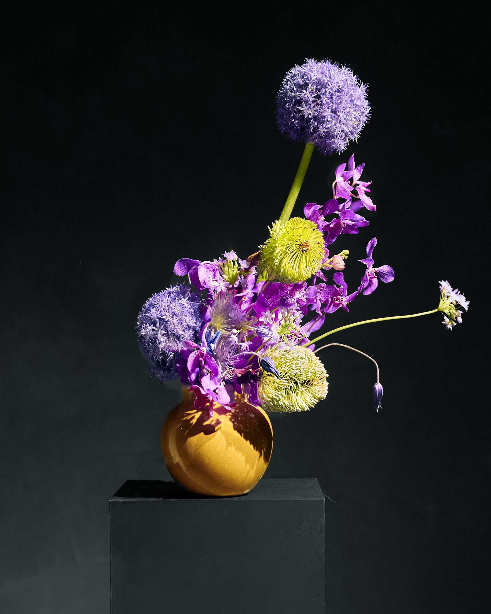 Allium, vanda orchid and green chrysanthemum in an ochre vessel